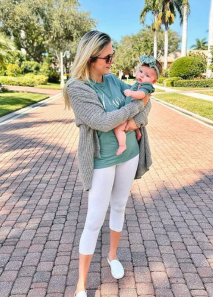 a mom holding her baby wearing matching green shirts