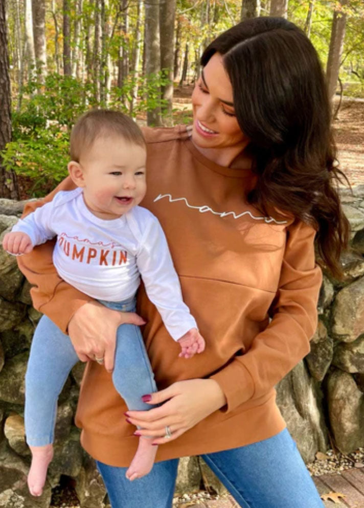 a mom holding her baby wearing matching “Mama” and “Mama’s Pumpin” shirts