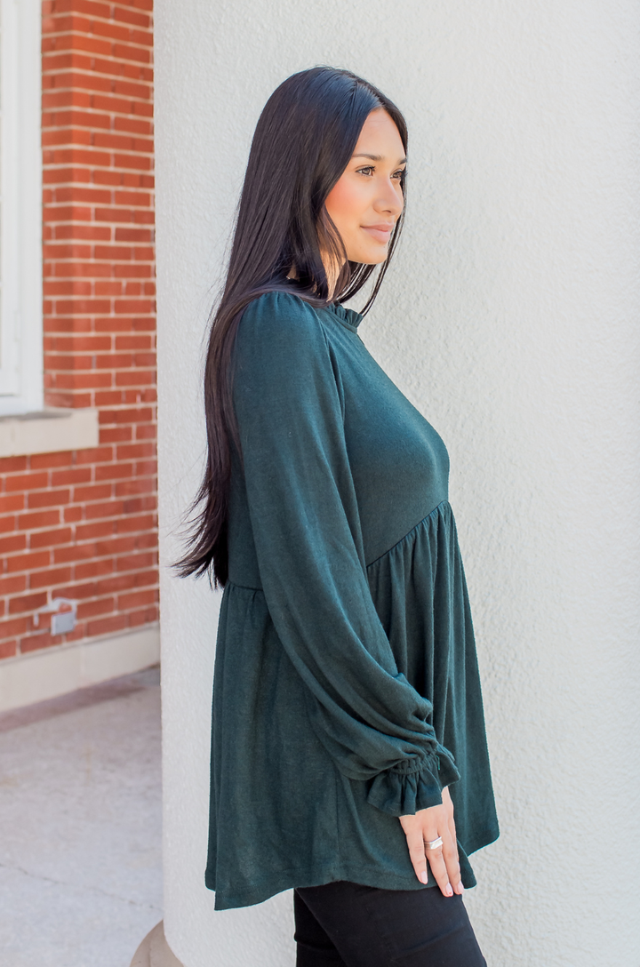 Side view of a model wearing the babydoll nursing sweater in deep green, showing a relaxed and flowy fit.