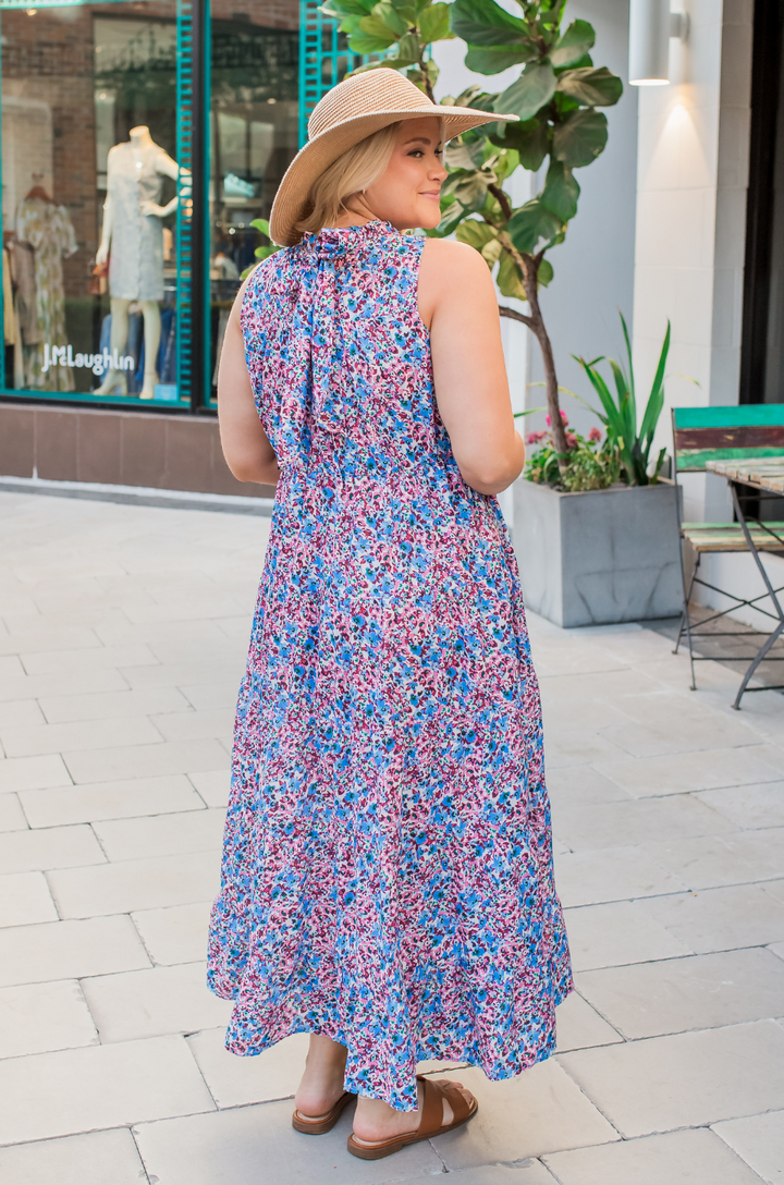 A side view shows a woman wearing the berry garden tie-back bow breastfeeding dress, highlighting the flowy fabric and comfortable drape away from the body.