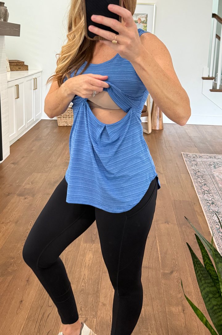 Mom wearing a blue athletic top and black leggings taking a mirror selfie showing the hidden nursing access 