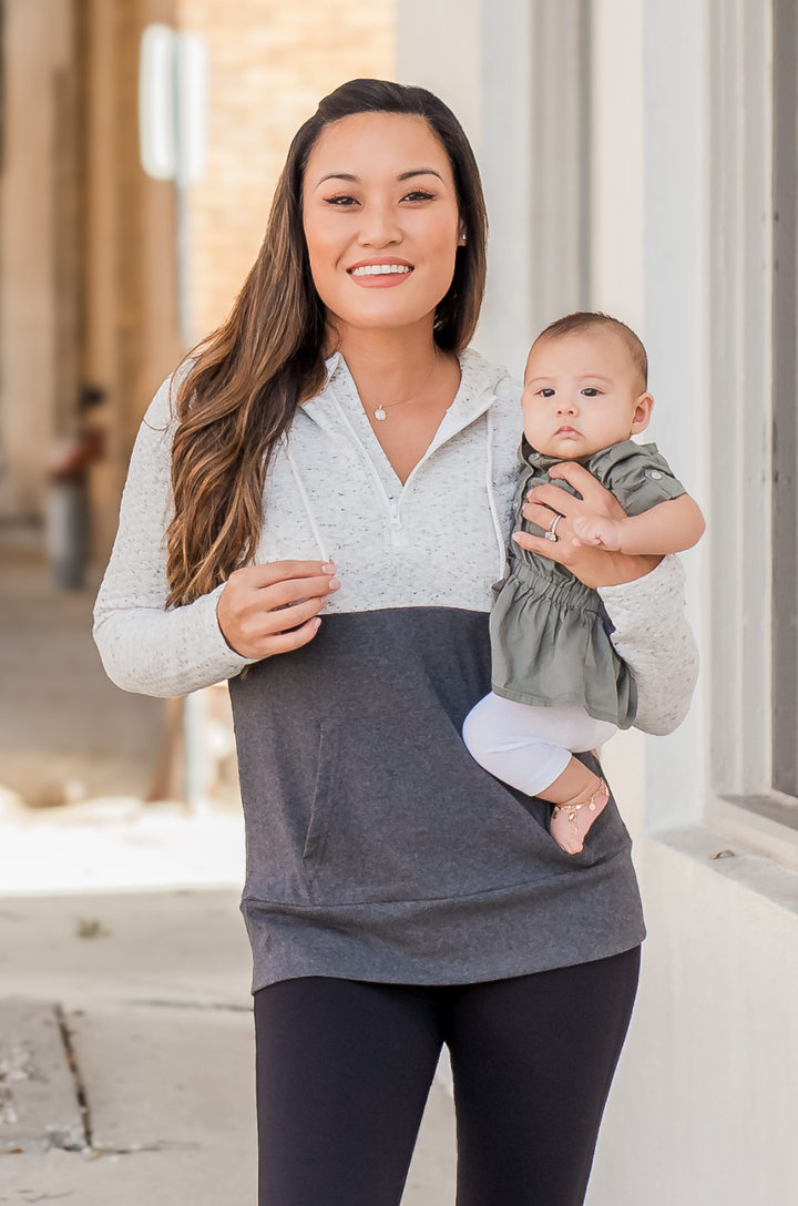 Breastfeeding mom wearing oatmeal waffle nursing hoodie, holding a baby at the chest with the quarter-zip neckline visible and concealed zipper breastfeeding access.