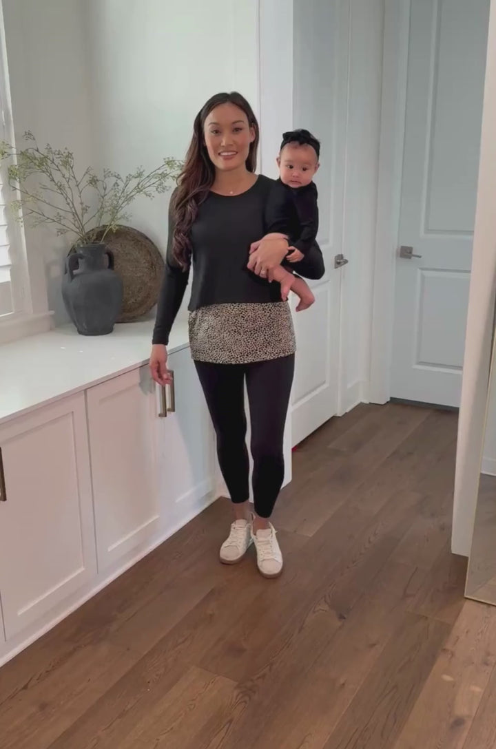 Video showing a mom wearing the black leopard print double layer nursing sweater, lifting the outer layer to demonstrate breastfeeding access.