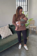 Woman nursing a baby in a brown yoga tunic