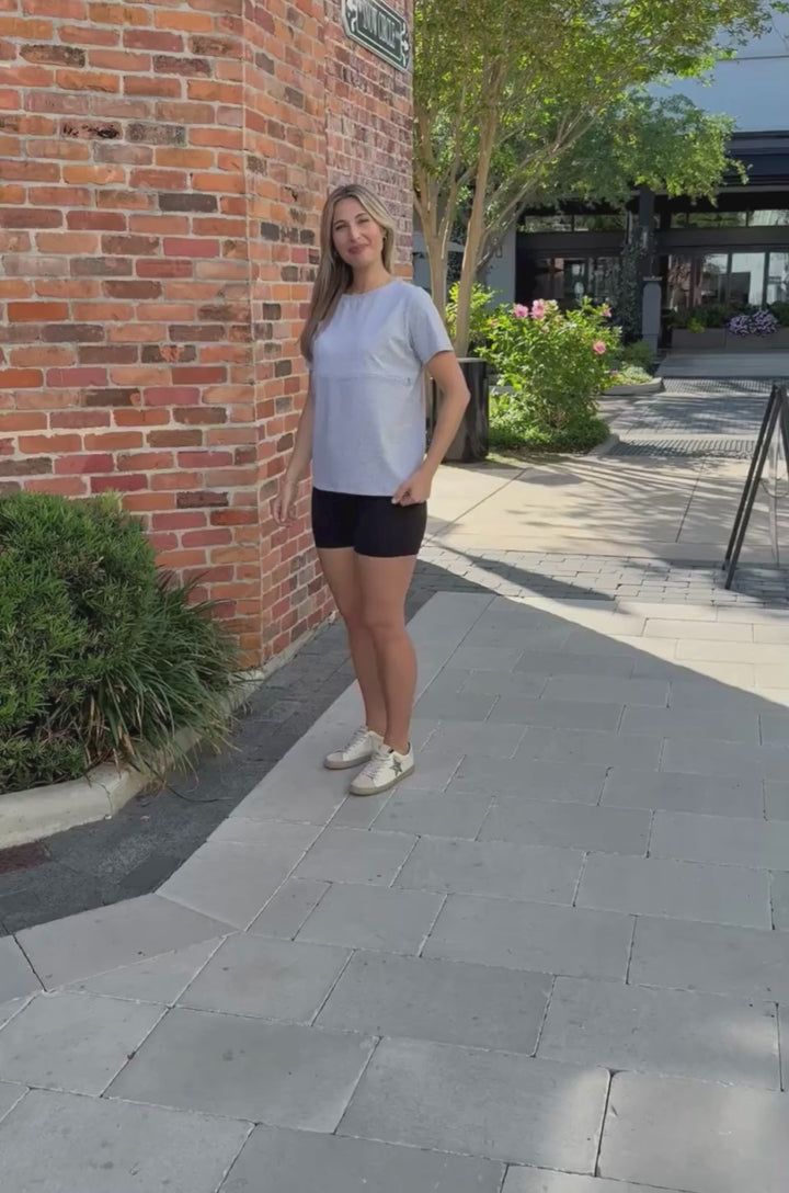 Video showing a mom wearing a heather gray cotton breastfeeding T-shirt and demonstrating hidden nursing access