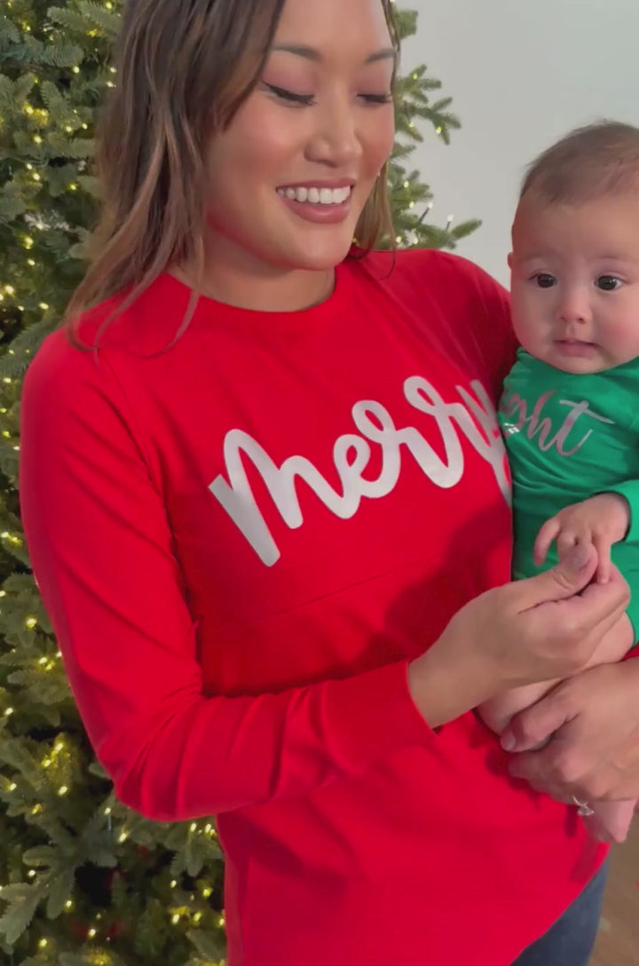 Breastfeeding mom wearing a red shirt that says "Merry" holding her baby with a matching green shirt that says "Bright".