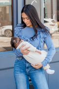 Mom wearing vintage blue ribbed ruffle shoulder nursing top, actively breastfeeding with the hidden zipper access opened behind the ruffle.