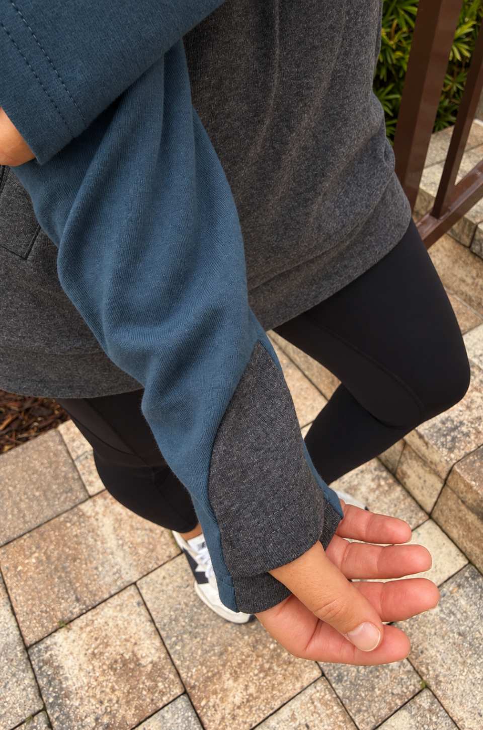 Close up of the thumbholes on a nursing pullover that is teal and dark gray