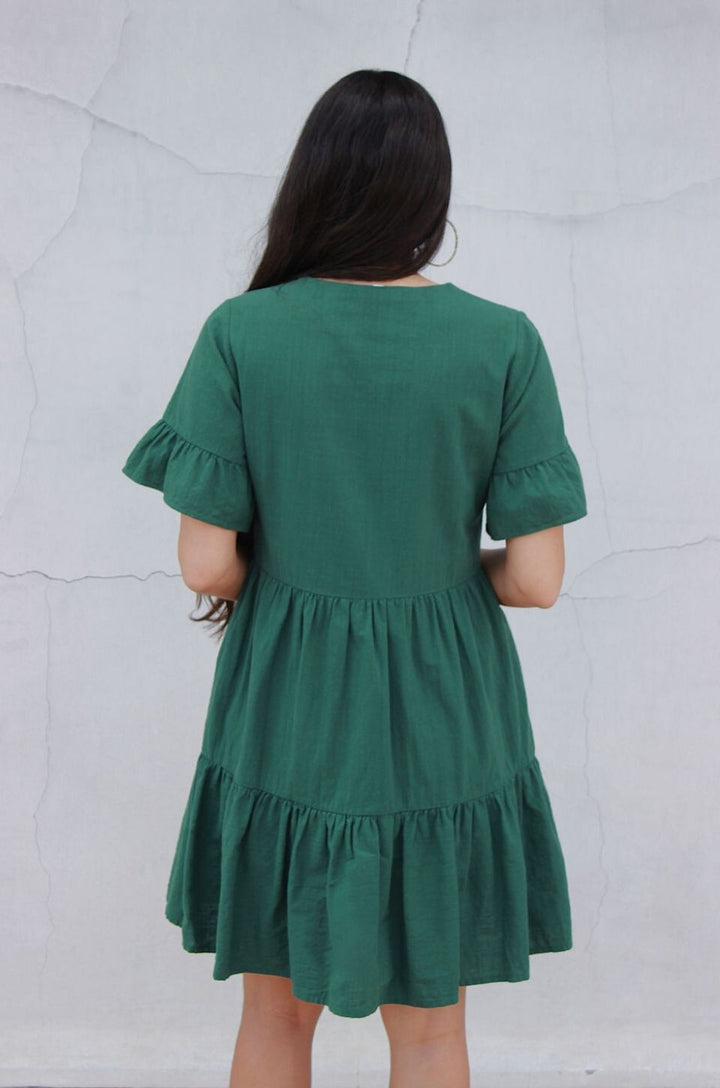 The back view of the green bell sleeve nursing dress with pockets highlights the relaxed fit and mid-length hemline.