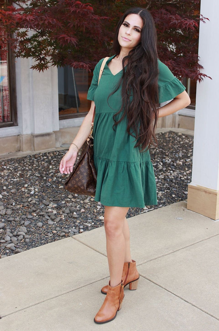 The green bell sleeve nursing dress with pockets is styled with flats for a casual, everyday breastfeeding outfit.