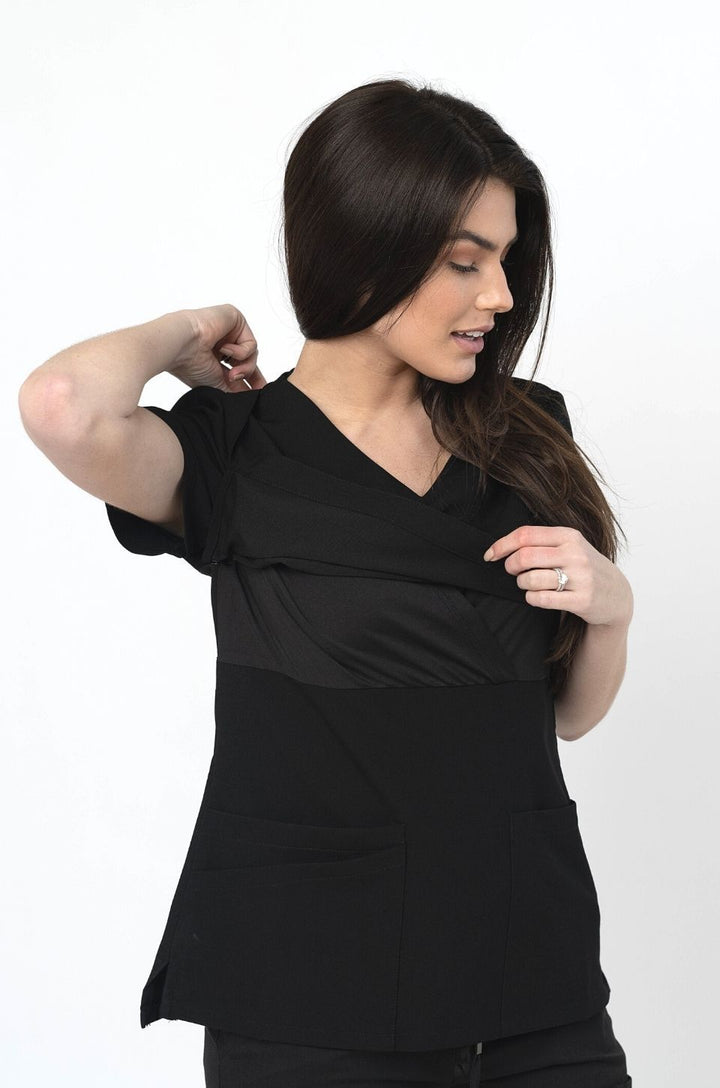 Close-up of overlapping fabric panels on black scrub top showing nursing access opening.