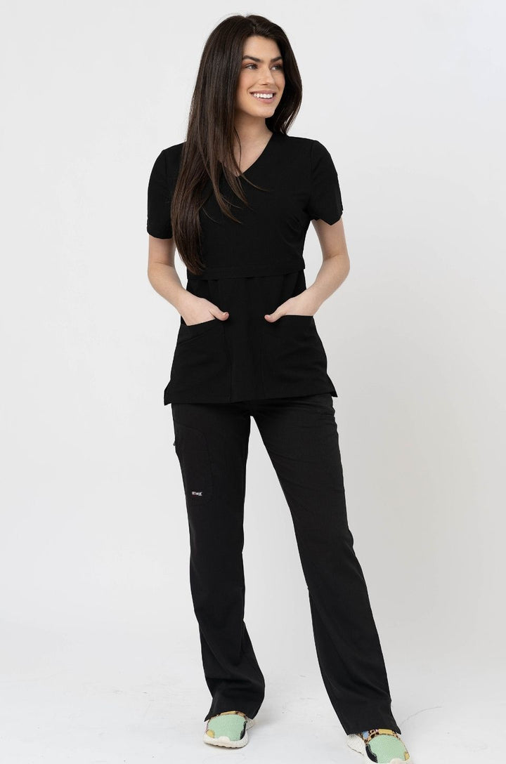 Breastfeeding mom wearing nursing scrubs, shown standing.